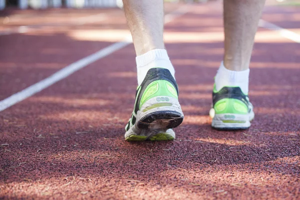 Feet in running shoes on stadium running path