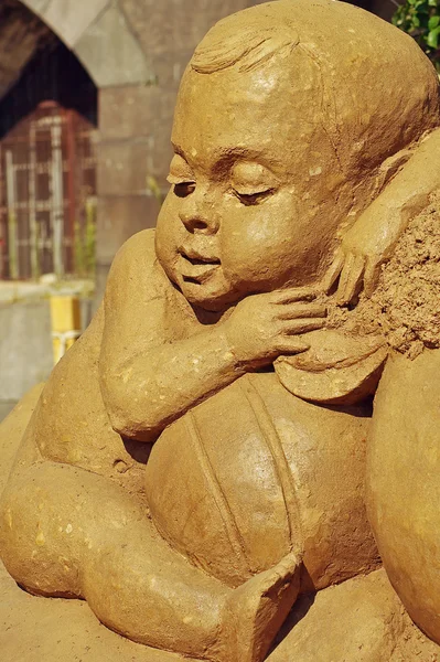International Sand Sculpture Festival  in Saint - Petersburg, August 3, 2014.Sculpture of a small child a seated among toys.