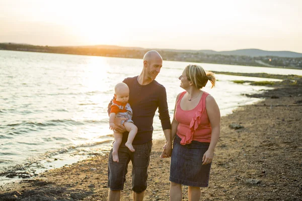 Family of three person is standing on sunset and sea backdrop