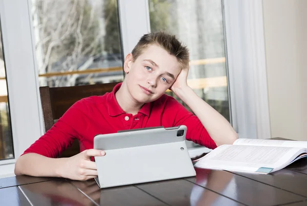Teen school boy studies hard over his book at home