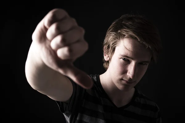 Teen showing thumbs down on the big black background