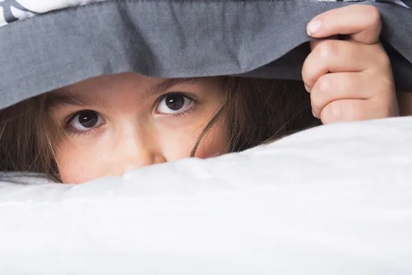 Child or teen under covers in bed