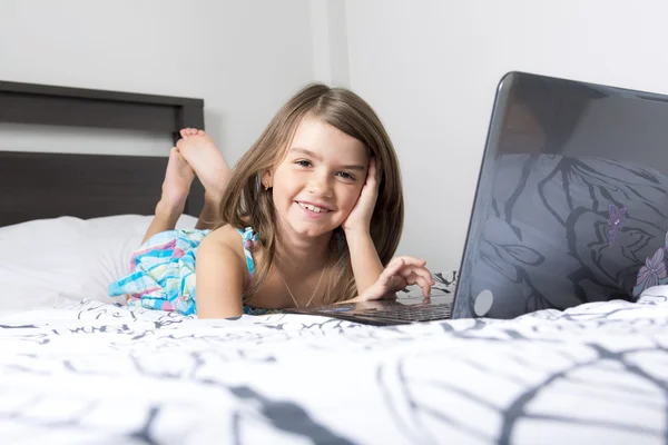 Nine years old child having fun using laptop at her bedroom