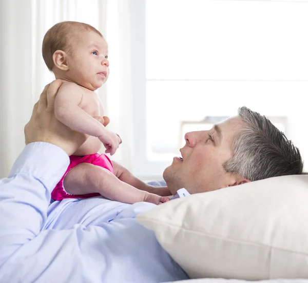 Father and is two months old baby in bed at home