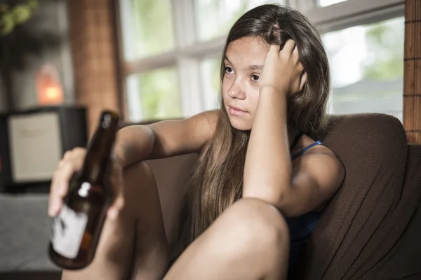 Sadness teen girl sits on sofa at home beer