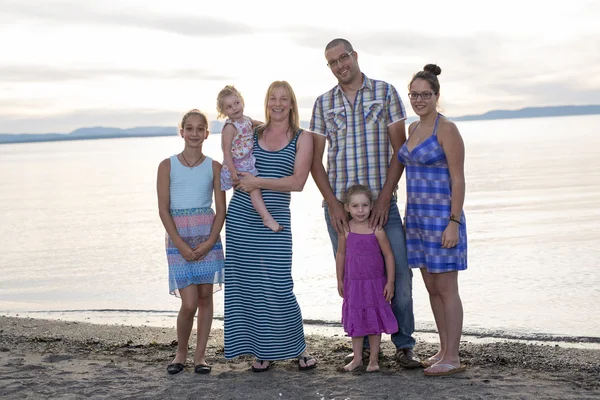 Happy beautiful family standing at beach sunset