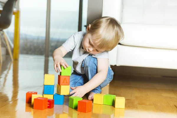 Kid playing toy blocks inside his house