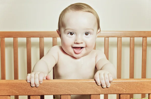 Funny little baby with beautiful standing in a round white crib