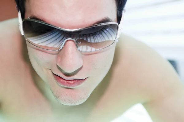 A man in a sunbath receiving high degree of ultraviolet light.