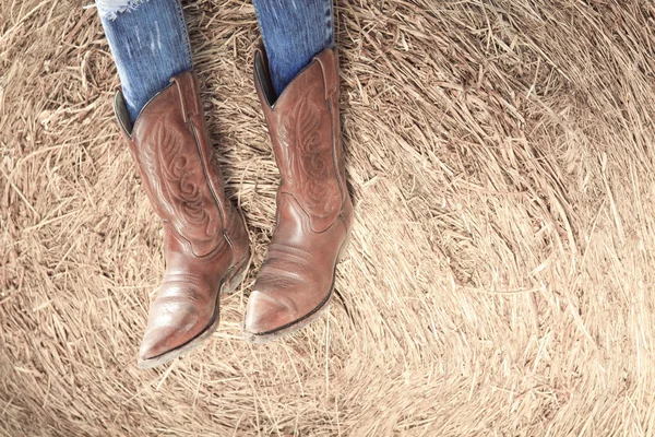 Western style image of cowgirls legs in jeans and boots on dese