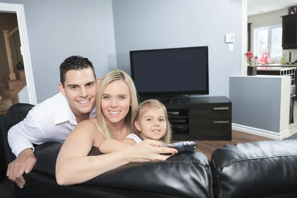 A Young family watching TV together at home