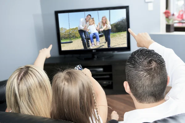 A Young family watching TV together at home