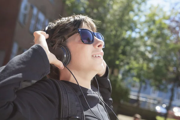 A teen boy listening to music with sun glasses