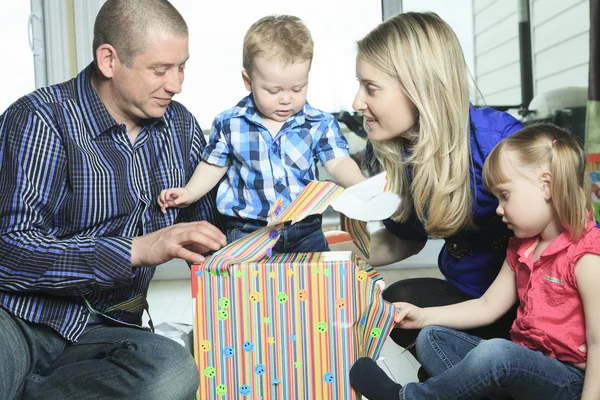 Parents offering a gift to their son in the living room