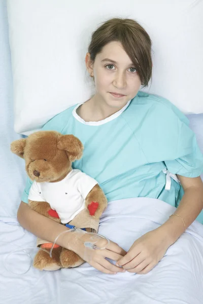 Little girl in hospital bed with teddy bear