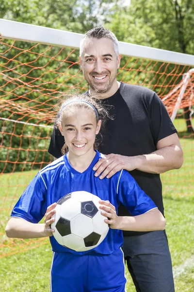 Teenager girl with his father play soccer in a beautiful day
