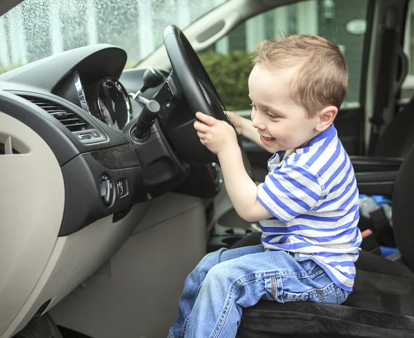 Cute little boy driving fathers car