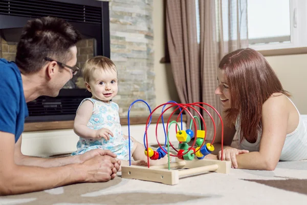 Parents baby sitting on floor play with toy