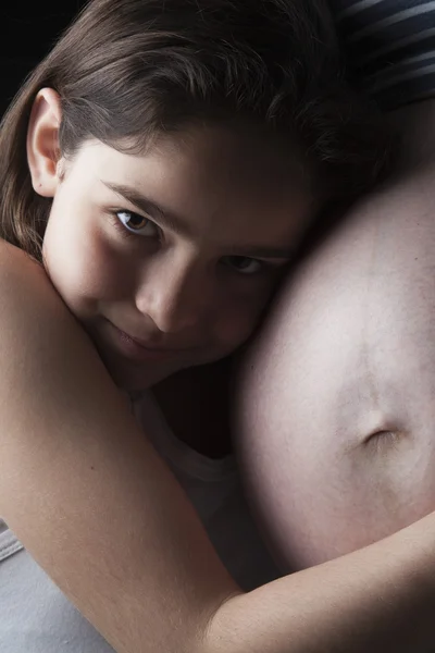 Beautiful little woman girl hugging pregnant mothers