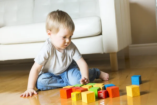 Kid playing toy blocks inside his house