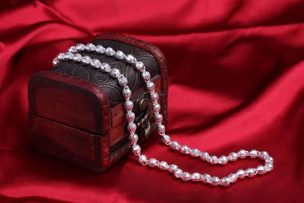 Silver necklace on red silk background