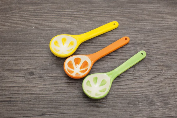 Spoons of different colors on wood background
