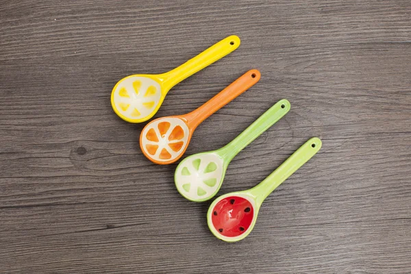 Spoons of different colors on wood background