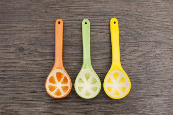 Spoons of different colors on wood background