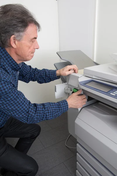 Frustrated man opening photocopy machine trying to fix problem