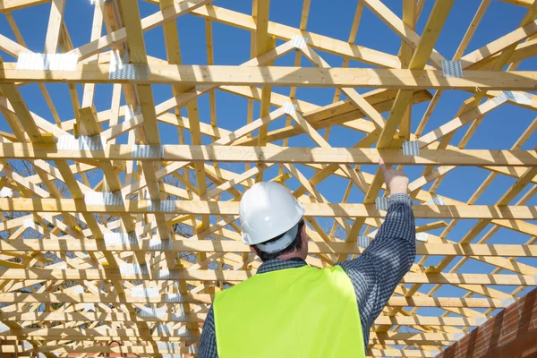 Building engineers standing over unfinished house with wooden roof structure