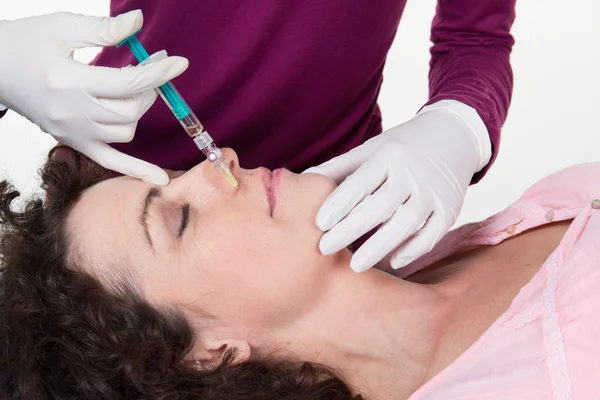 Middle aged woman receiving a botox injection face close up