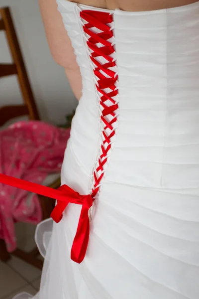 Back of wedding dress of a bride with red ribbon