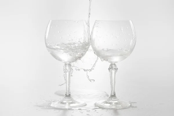 Water pouring from bottle into the glass, isolated on white