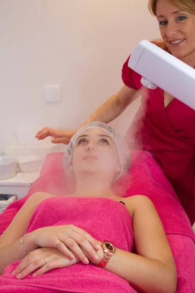 Relaxing during a facial steam treatment at a beauty spa.