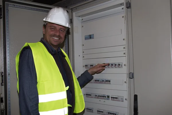 Man Electrician builder worker in front of fuse switch board
