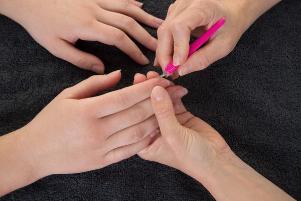 Woman in nail salon receiving a manicure by female beautician