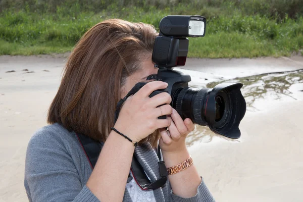 Young woman photographer is taking pictures outdoors