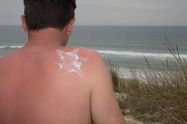 Woman putting sun tan lotion on man at the beach