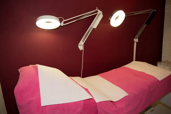 Pink empty massage table in room with light