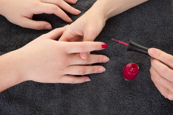 Picture of woman hands putting a varnish on nails