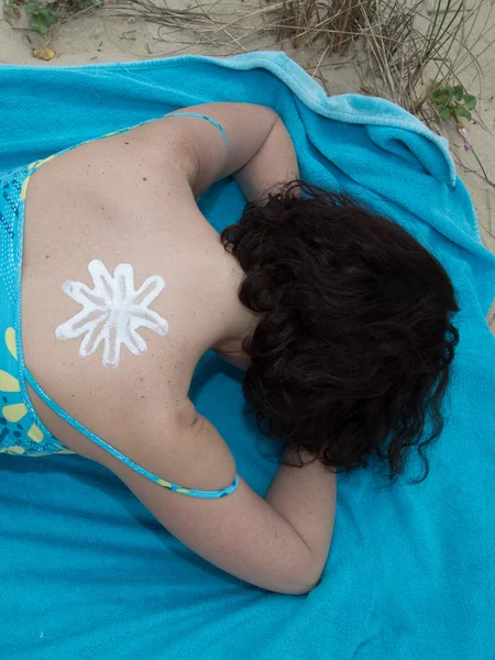 Woman with suntan lotion at beach in form of sun