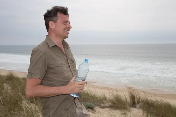 Caucasian man posing at the beach - with a bottle of water in hands