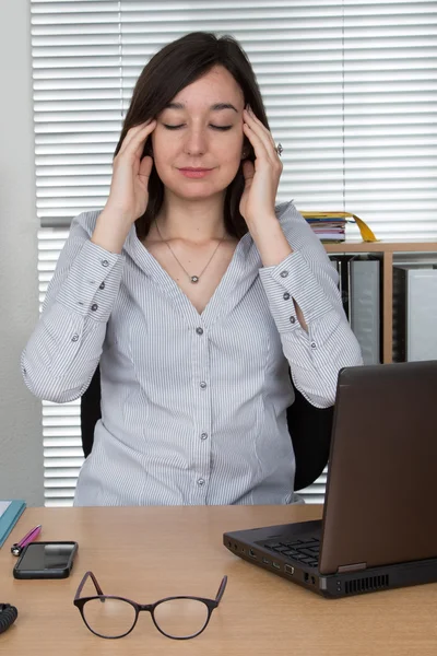 Tired office worker with headache touching her temples.