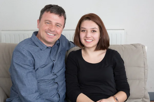 Happy couple thinking and sitting on a couch at home