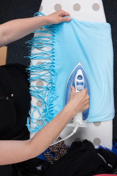 Woman ironing clothes on ironing board, closeup flat lay
