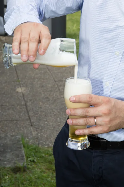 Man pouring beer in a glass outside at summer