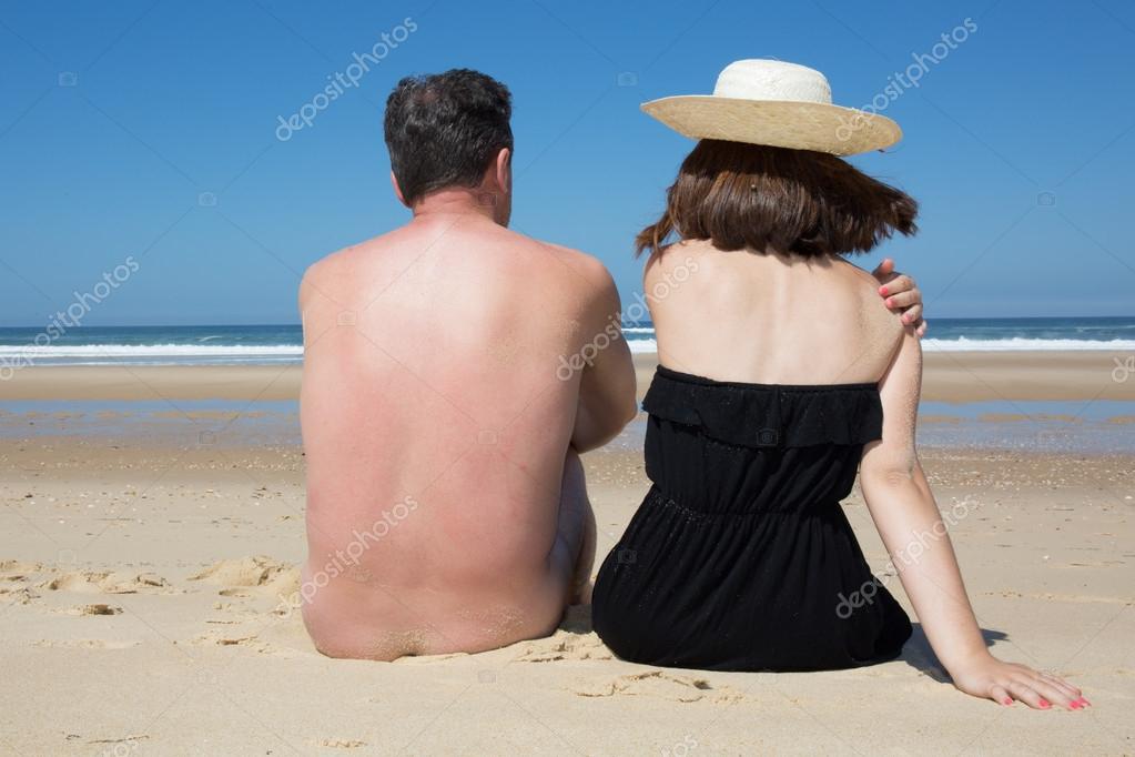 Голый мужчина с женщиной сидящей на пляже стоковое фото OceanProd