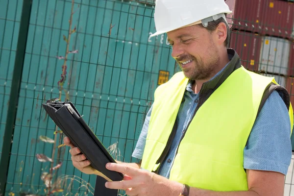 Happy man Logistics manager at container transhipment plant, with an electronic tablet