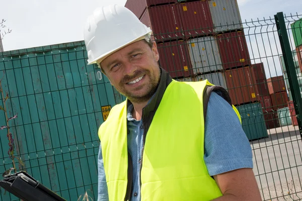 Happy man Logistics manager at container transhipment plant, with an electronic tablet