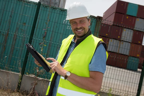 Happy man Logistics manager at container transhipment plant, with tablet